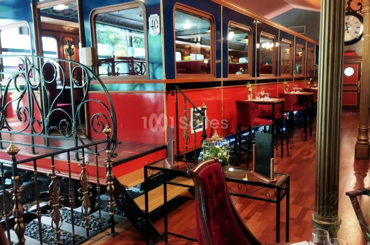 Intérieur d'un restaurant aménagé dans un décor de wagon de train avec tables, chaises et ambiance rétro.