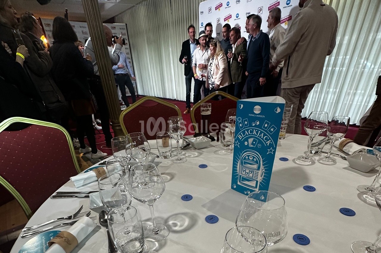 Groupe de personnes posant devant un mur de logos dans une salle, avec une table dressée au premier plan.