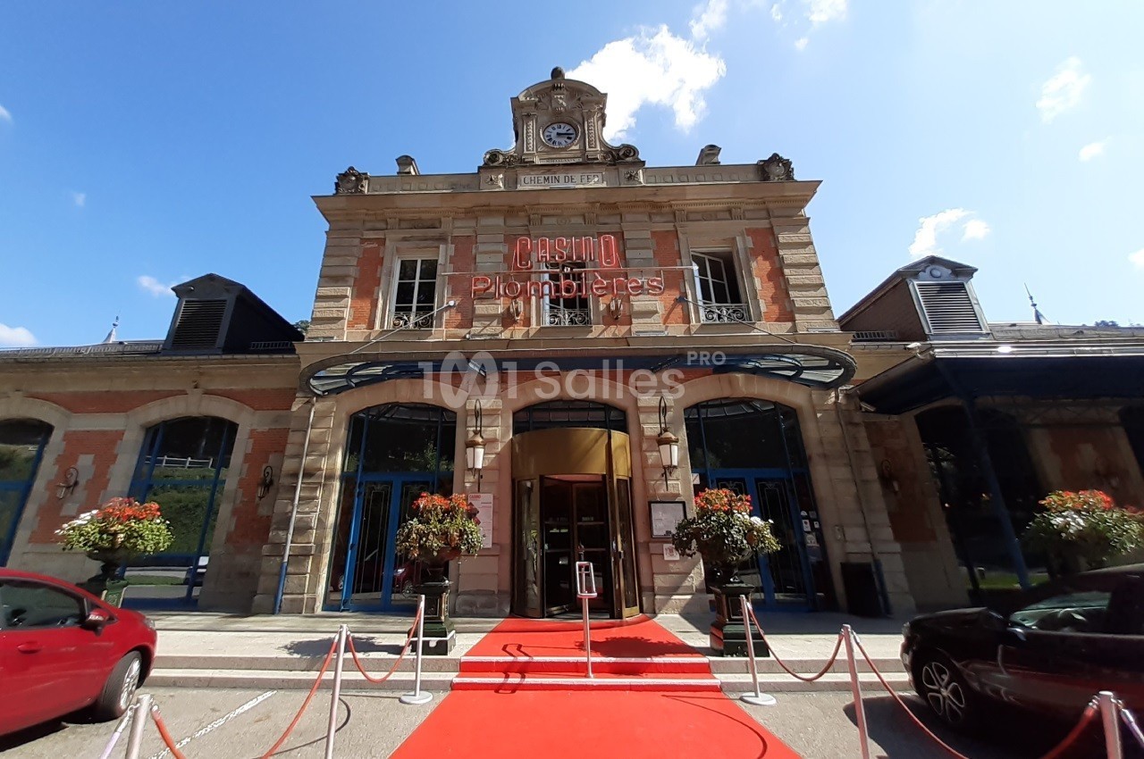 Façade du casino de Plombières-les-Bains avec une entrée ornée d'un tapis rouge et des fleurs en extérieur.