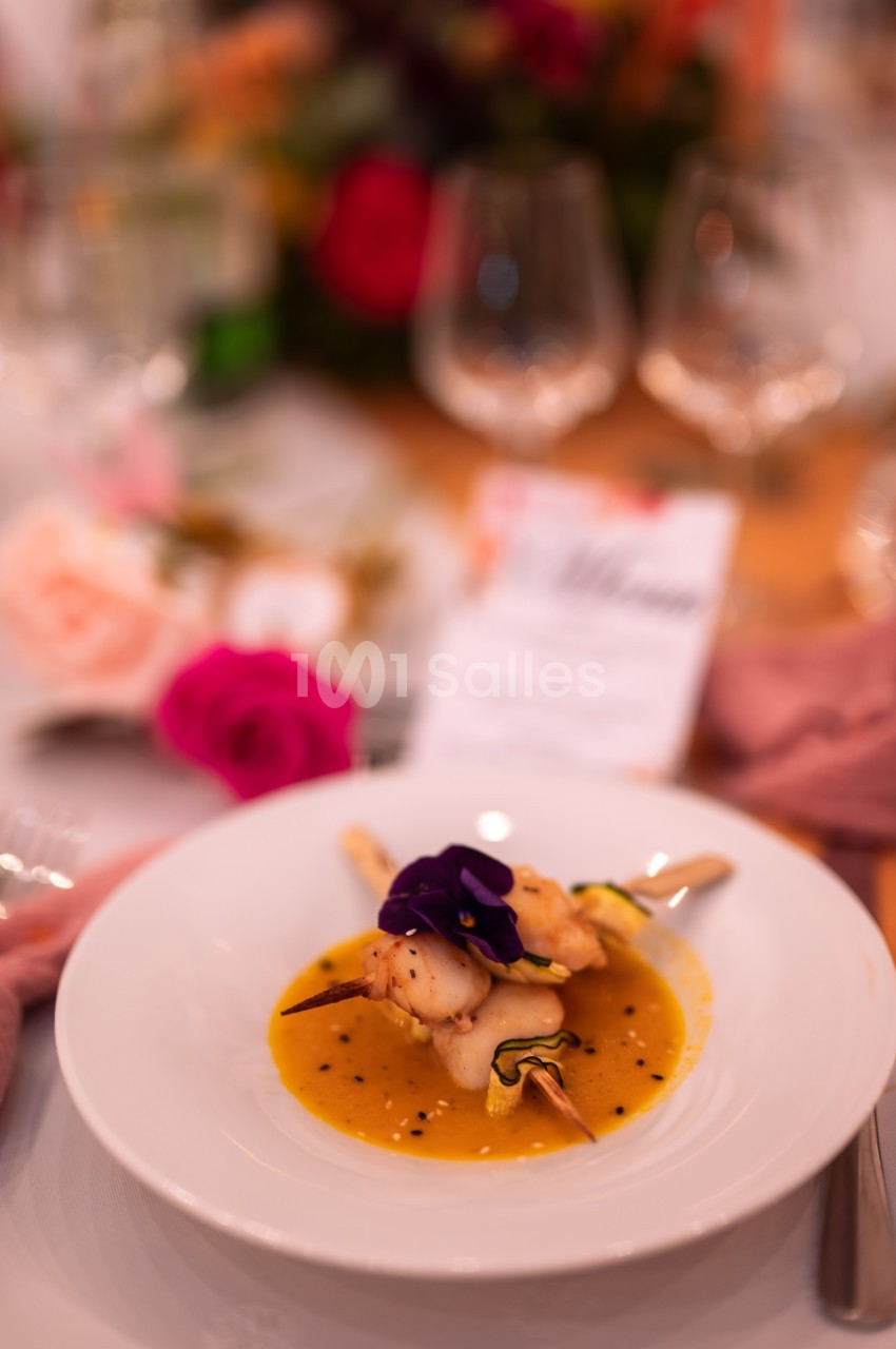 Assiette gastronomique avec une entrée raffinée composée de légumes, sauce jaune et décoration florale comestible.