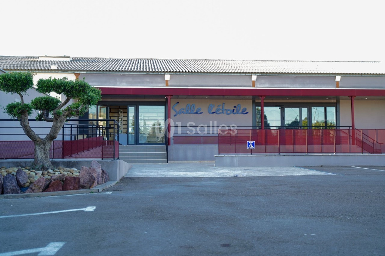 Façade d'une salle de réception avec une entrée accessible et un parking devant.
