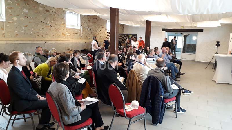 Un groupe de personnes assises dans une salle, participant à une réunion ou une présentation.