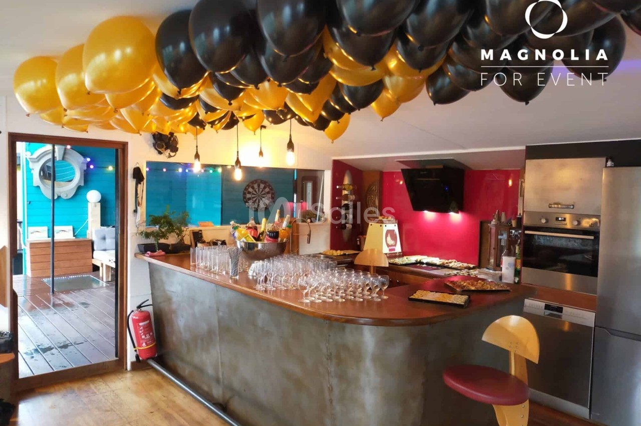 Ballons noirs et jaunes décorant un bar intérieur avec des verres alignés et un buffet en arrière-plan.