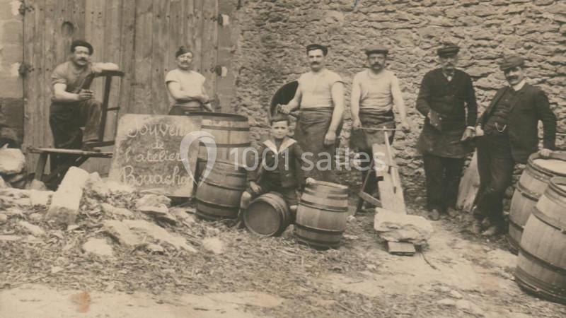 Groupe d'hommes posant devant des tonneaux et une pancarte indiquant ’Souvenir de l'atelier Bordachon’.