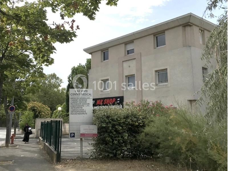 Bâtiment beige à trois étages entouré de végétation, avec un panneau indiquant un centre médical à l'entrée.