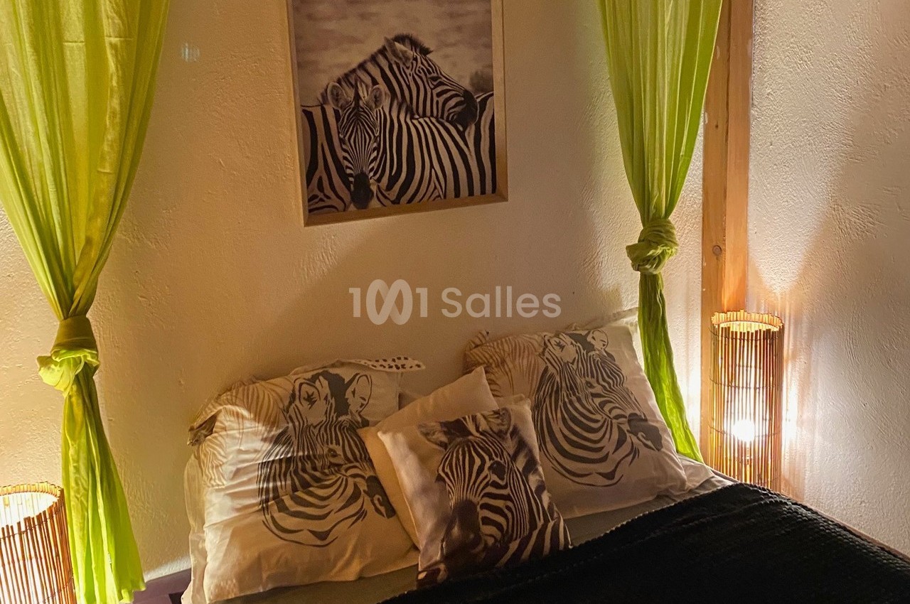 Lit décoré avec des coussins à motifs de zèbres, encadré par des rideaux verts et éclairé par des lampes d'appoint.