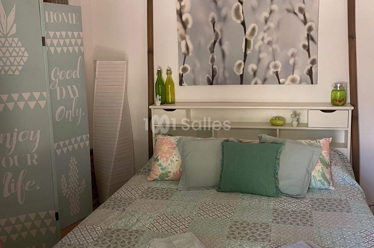 Chambre lumineuse avec lit aux tons pastel, tableau de chatons de saule, paravent décoratif et objets décoratifs assortis.