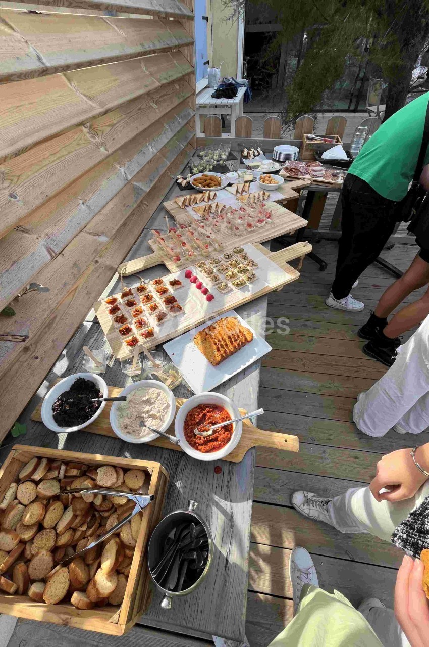 Buffet en extérieur avec divers plats, toasts, tartinades et amuse-bouches présentés sur une table en bois.