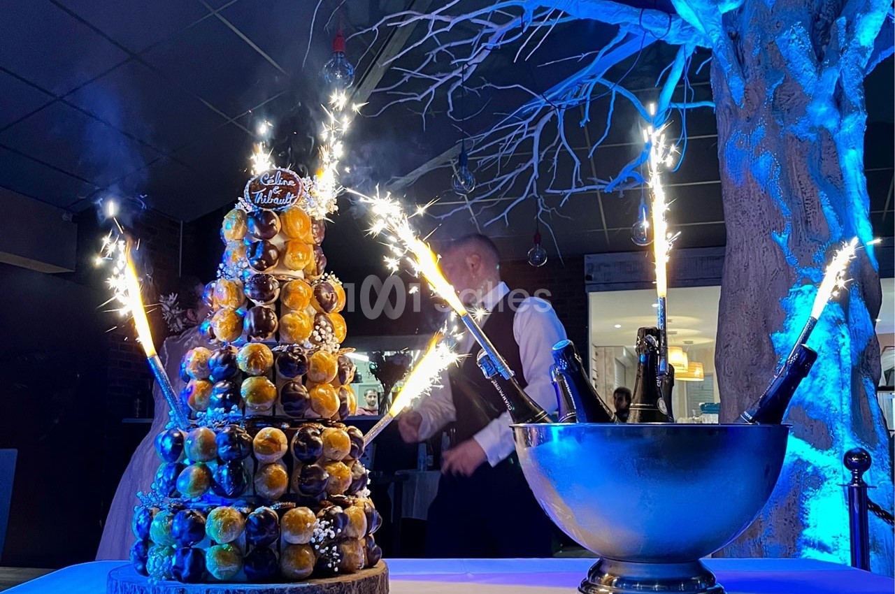 Pièce montée éclairée par des cierges magiques, accompagnée d'un seau à champagne, dans une ambiance festive.