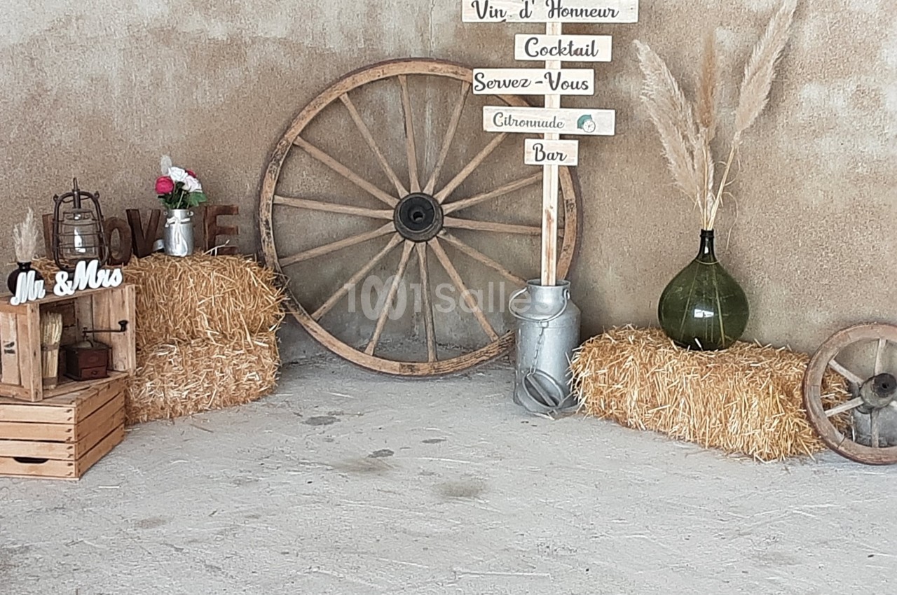 Décoration champêtre avec bottes de paille, roue en bois, pancartes directionnelles et accessoires rustiques.