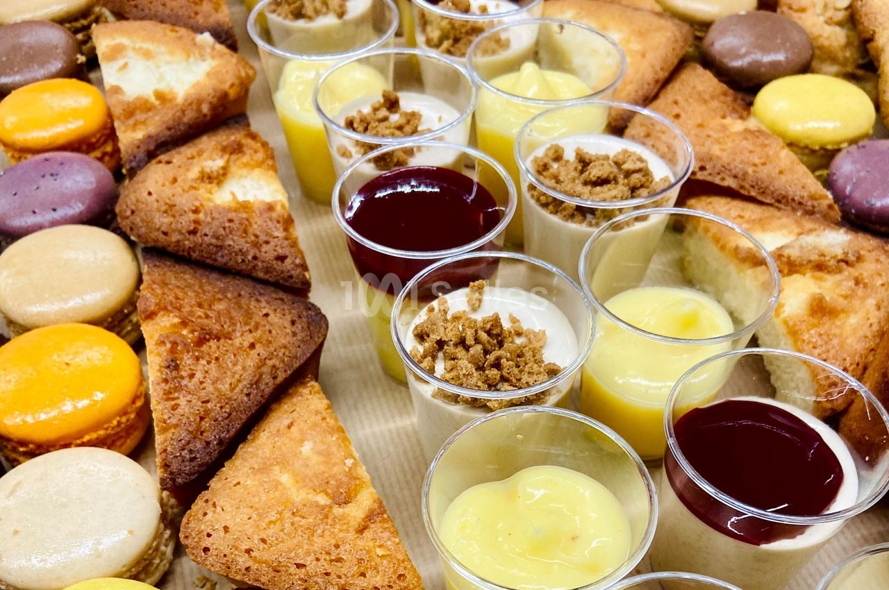 Plateau de desserts variés comprenant macarons, parts de gâteau et verrines de mousses et crèmes.