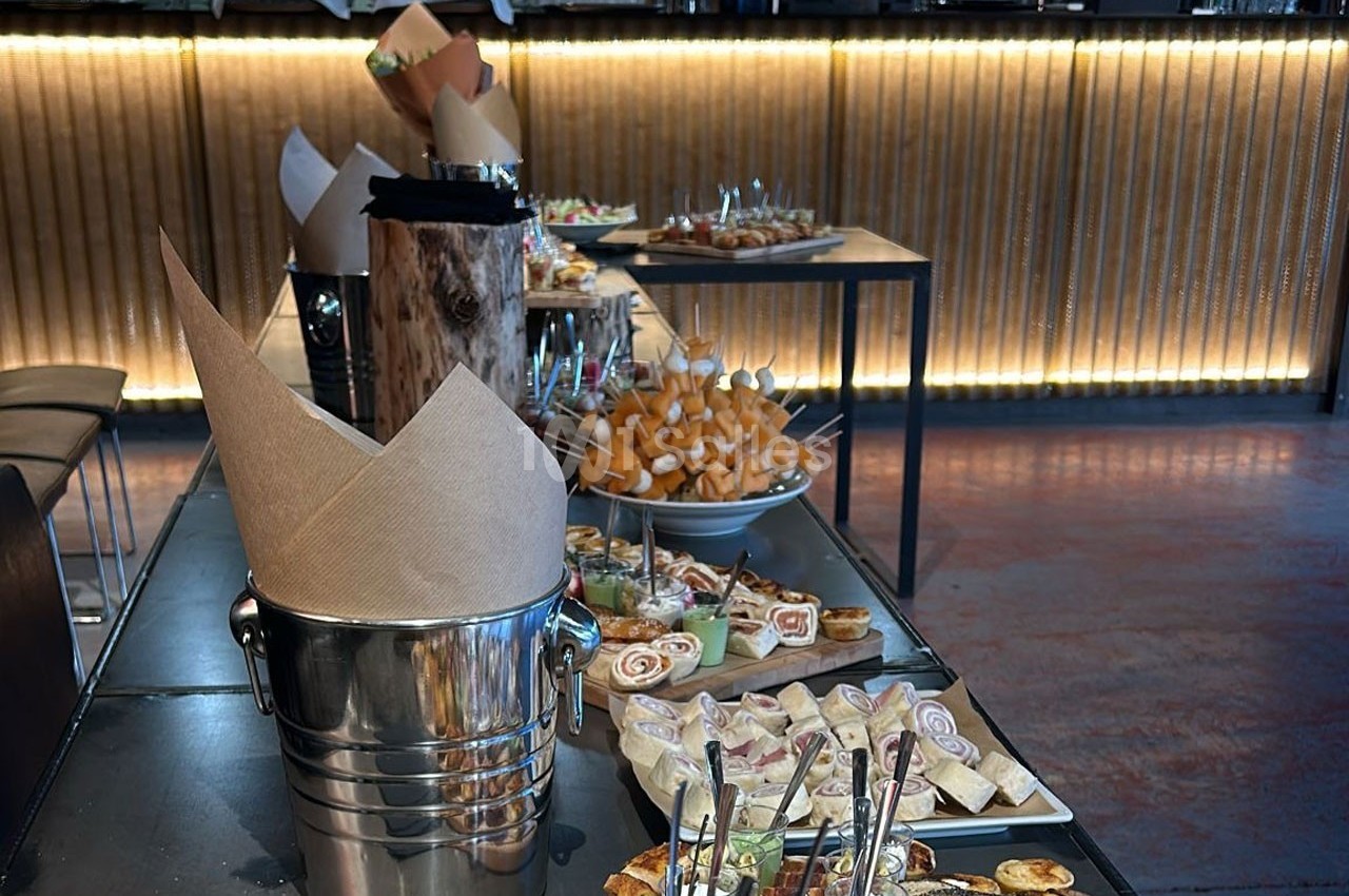 Buffet avec divers amuse-bouches et plats disposés sur des tables dans un espace intérieur éclairé.