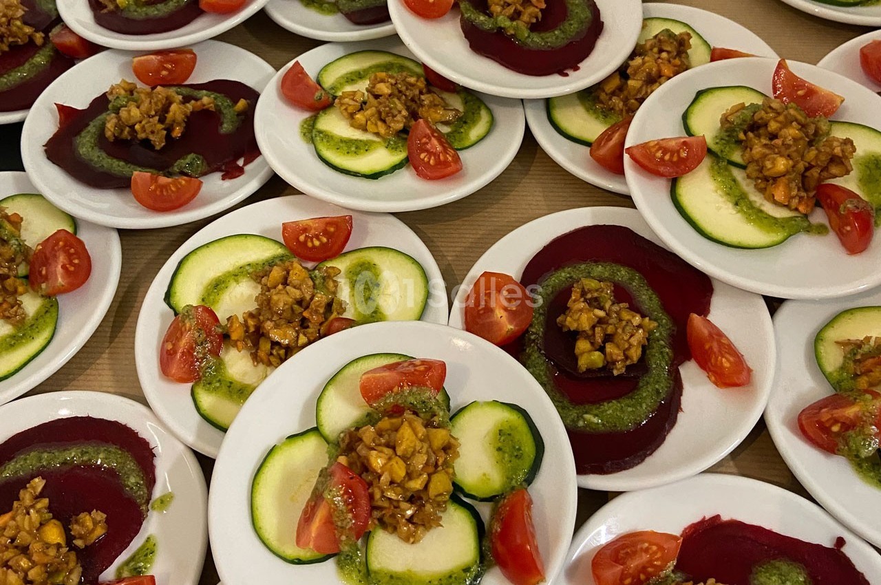 Assiettes garnies de tranches de betterave et courgette, tomates cerises et noix avec sauce verte.