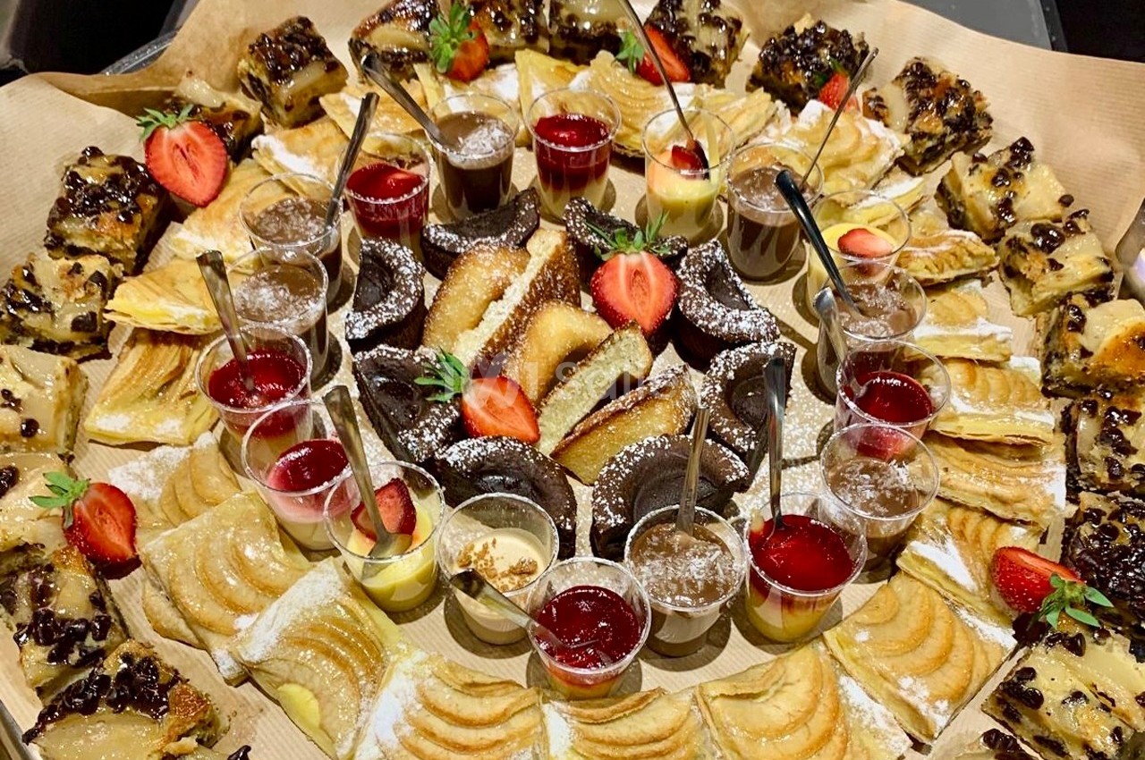Plateau de desserts variés avec parts de gâteaux, tartes aux fruits, verrines et fraises fraîches en décoration.