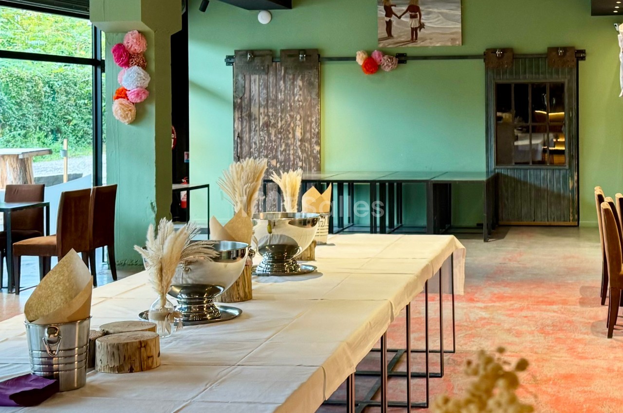 Salle décorée avec des tables dressées, ornées de bouquets de fleurs séchées et de seaux métalliques, ambiance chaleureuse.