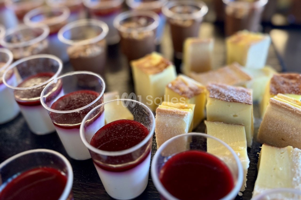 Desserts variés comprenant verrines de panna cotta aux fruits rouges et parts de flan disposés sur une table.