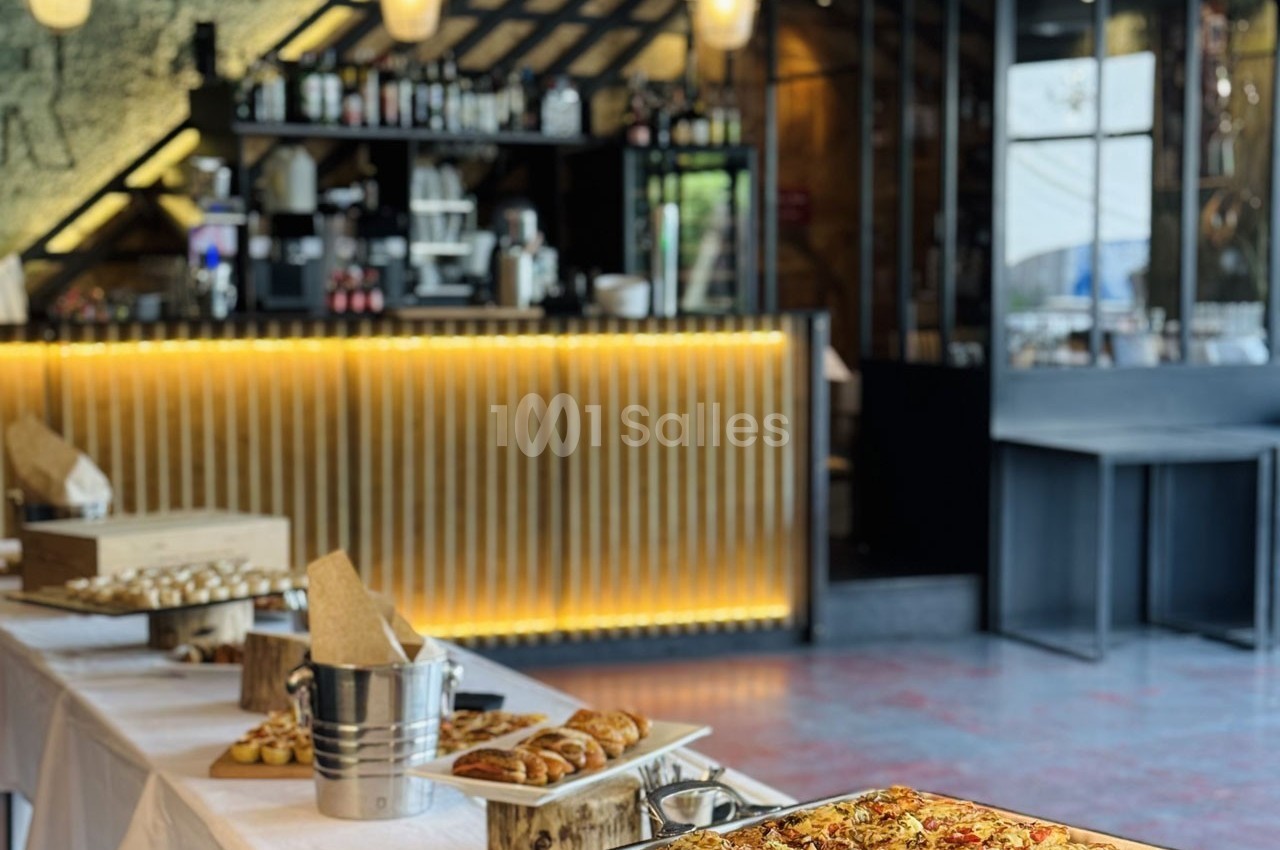 Buffet avec viennoiseries, pizzas et desserts disposés sur des tables dans un restaurant au décor moderne.