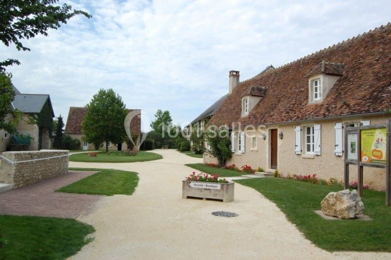 Chemin pavé bordé de maisons traditionnelles en pierre avec toits en tuiles, entouré de verdure.