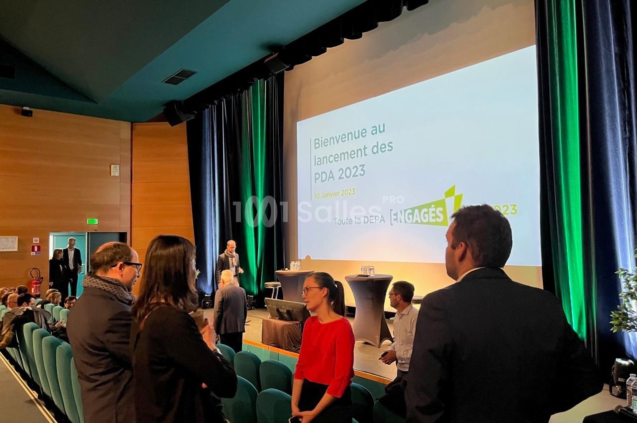 Des personnes discutent dans une salle de conférence avec un écran affichant ’Bienvenue au lancement des PDA 2023’.