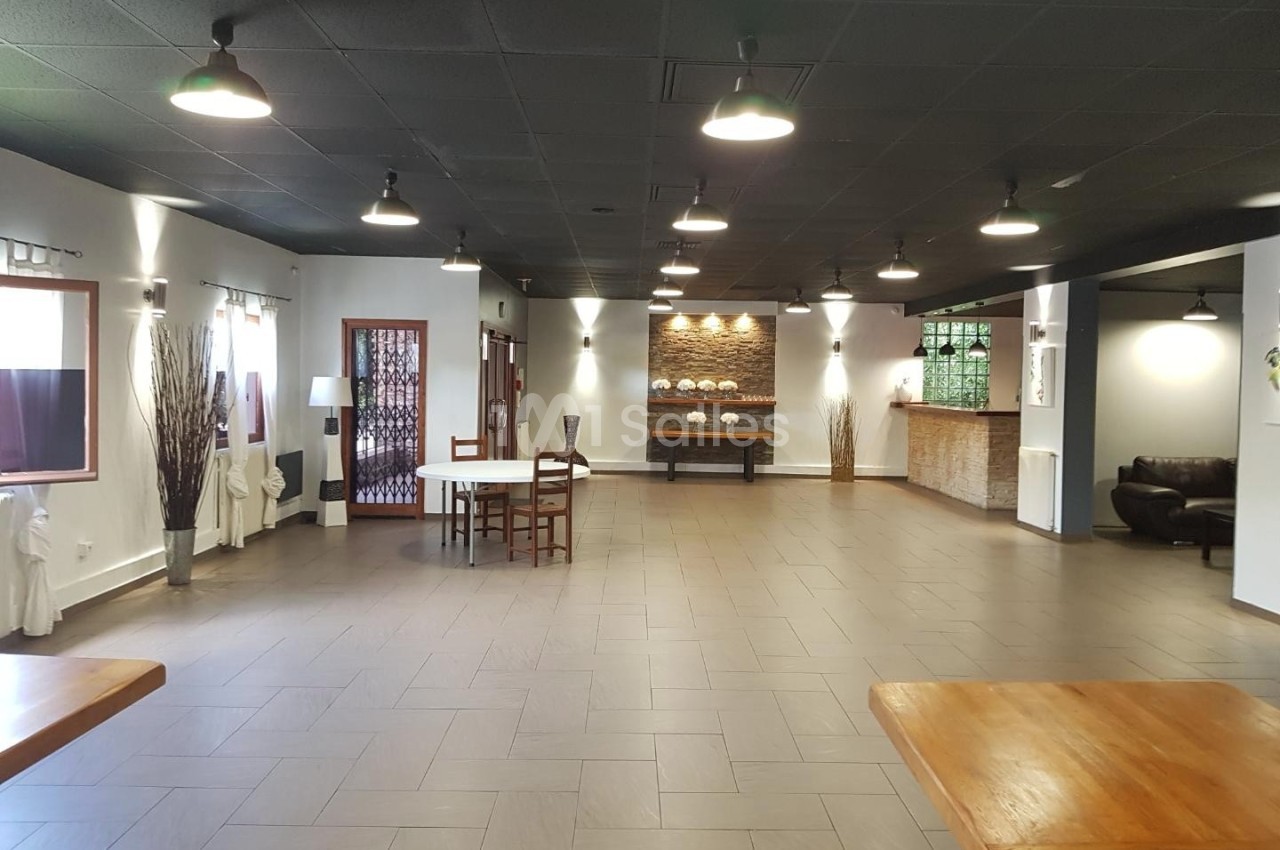 Salle spacieuse avec sol en carrelage, plafond noir, tables en bois, éclairage suspendu et décoration sobre.