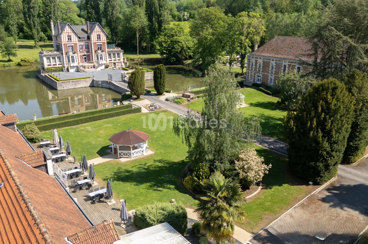 Vue aérienne d'un domaine avec un étang, un bâtiment principal, un kiosque, des jardins et des arbres.