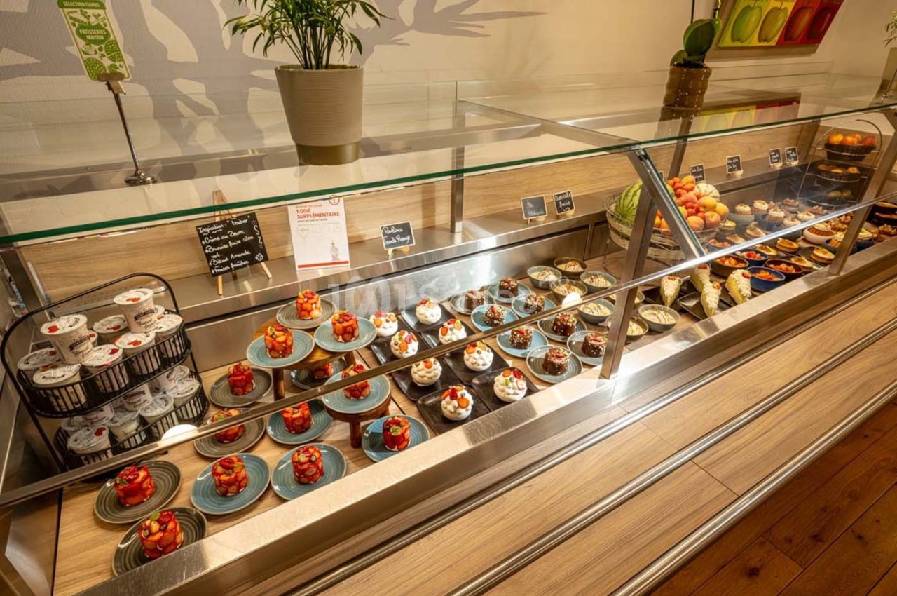 Vitrine réfrigérée présentant une variété de desserts, notamment des pâtisseries et des verrines, dans un cadre lumineux.