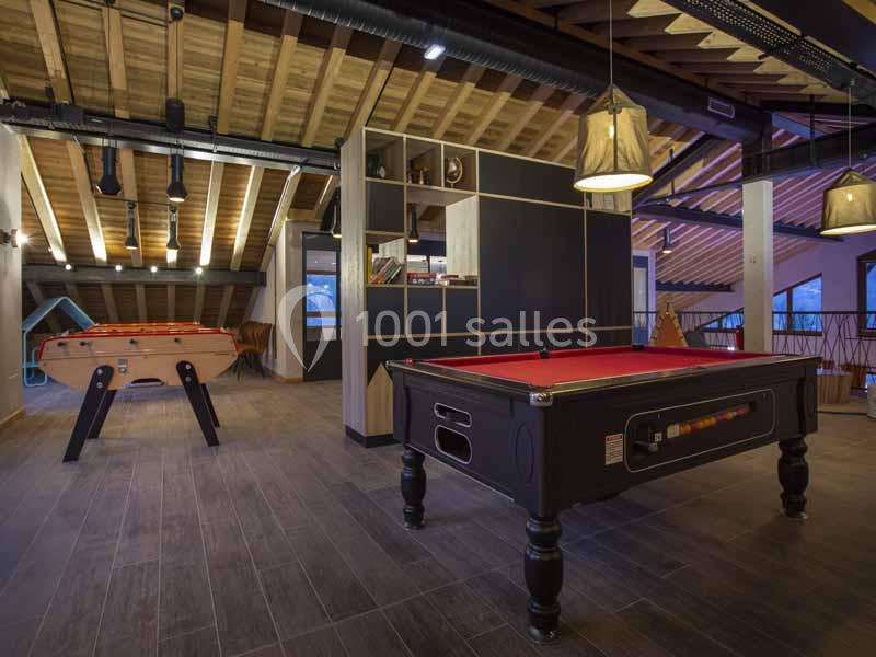 Salle de jeux avec un baby-foot et une table de billard dans un espace à la décoration moderne et plafond en bois.