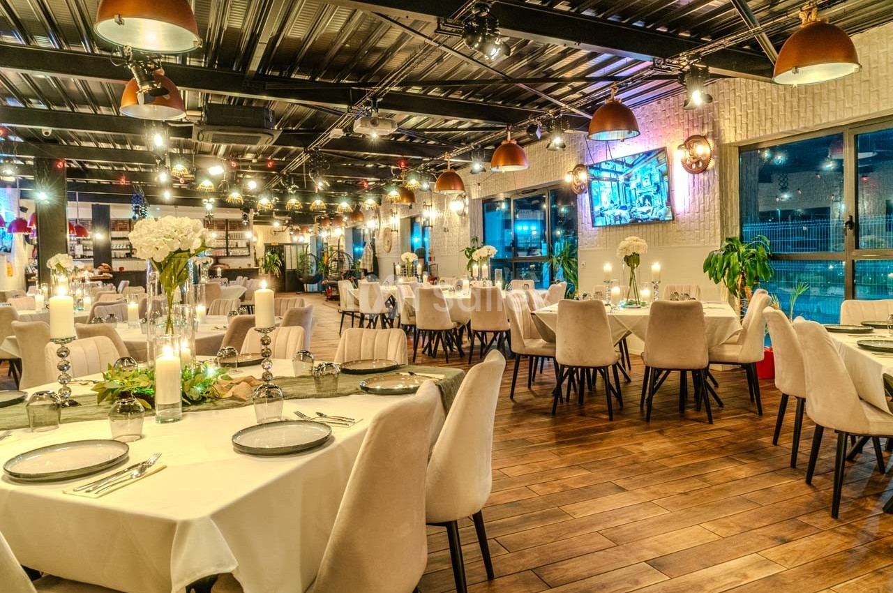 Salle de restaurant élégante avec tables dressées, éclairage chaleureux et décoration moderne.