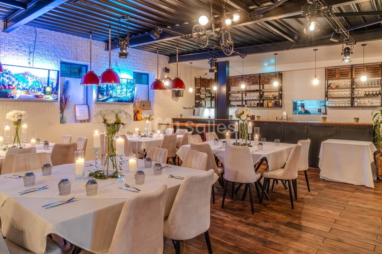 Salle de restaurant élégamment décorée avec des tables dressées, éclairage chaleureux et bar en arrière-plan.