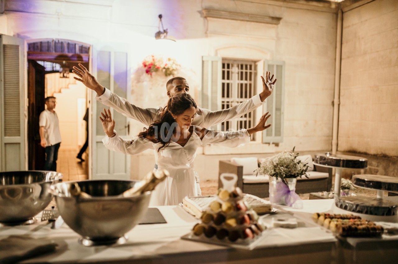 Un couple danse joyeusement devant une table dressée avec des desserts et des décorations lors d'une réception en soirée.
