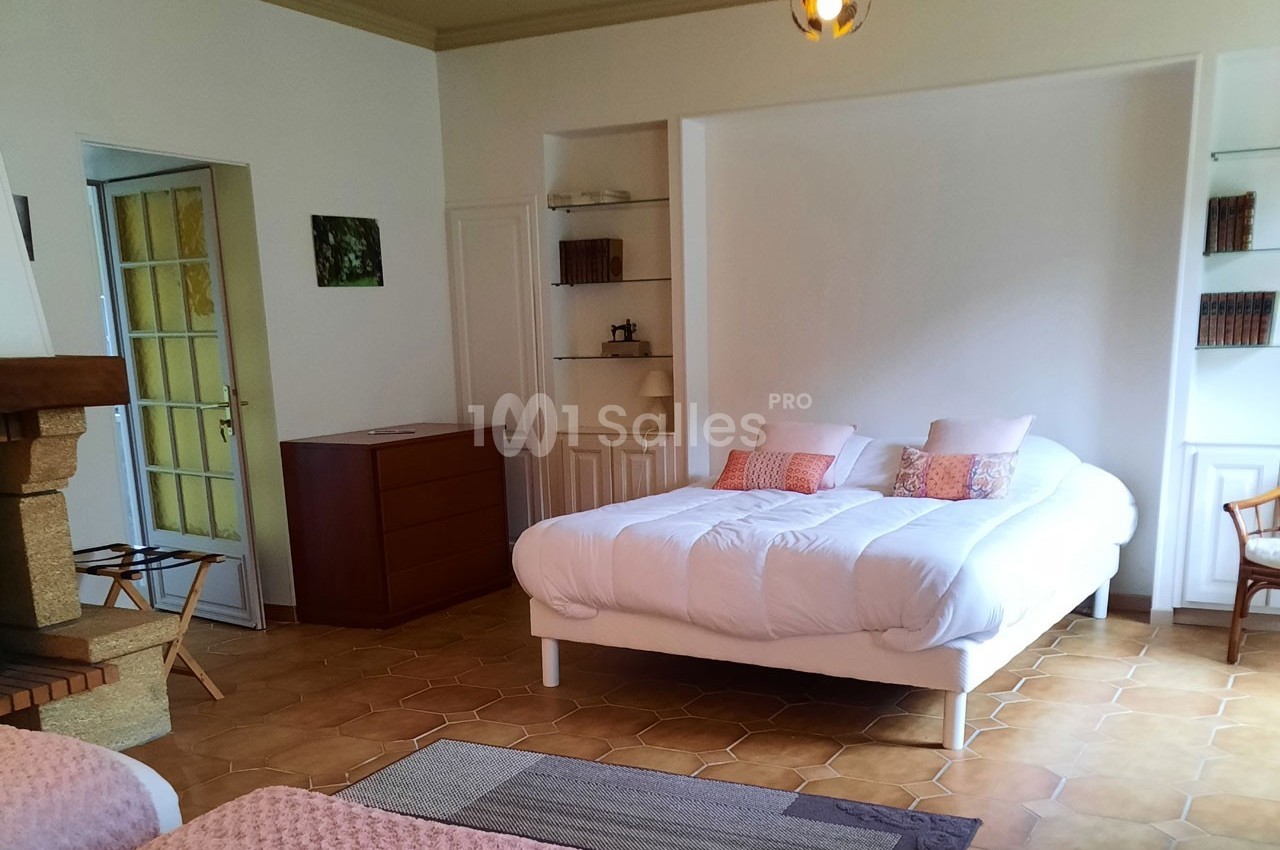 Chambre lumineuse avec un lit double, des étagères intégrées, une commode et un sol en carrelage.