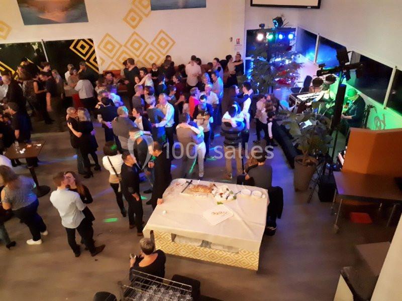 Groupe de personnes dans une salle lors d'une soirée dansante avec éclairages colorés et buffet au premier plan.
