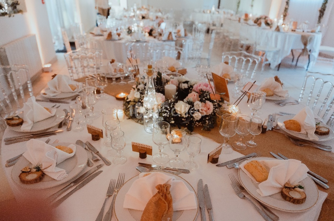 Table de réception élégamment dressée avec nappes blanches, vaisselle raffinée et centre de table floral.