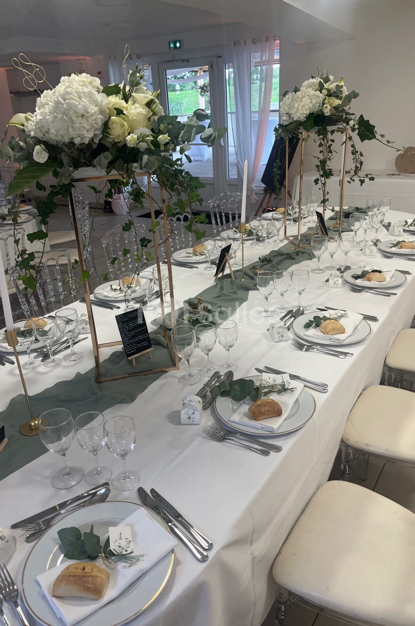 Table de réception élégamment dressée avec nappes blanches, centres de table fleuris et vaisselle raffinée.