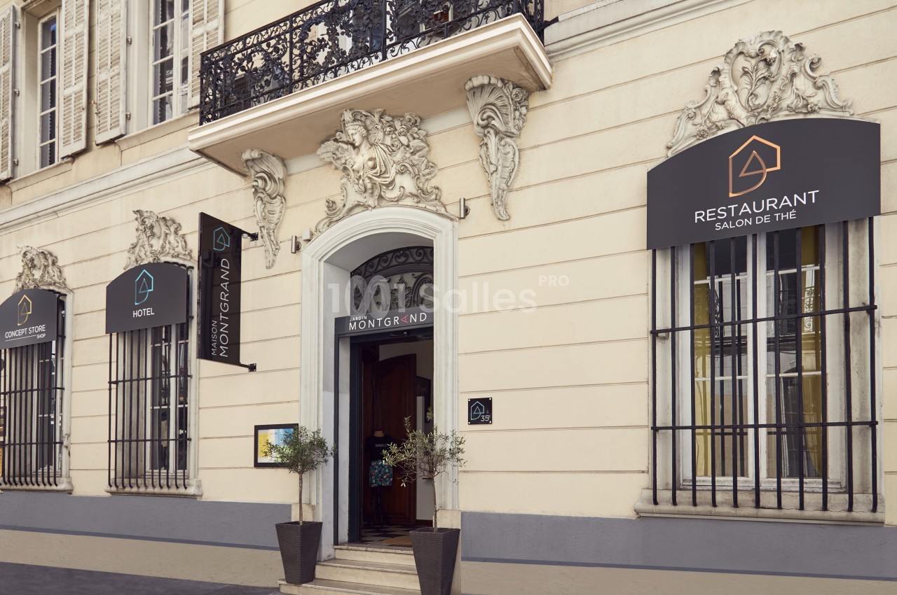 Façade d'un bâtiment avec entrée principale, enseignes d'hôtel et restaurant, et décorations architecturales.
