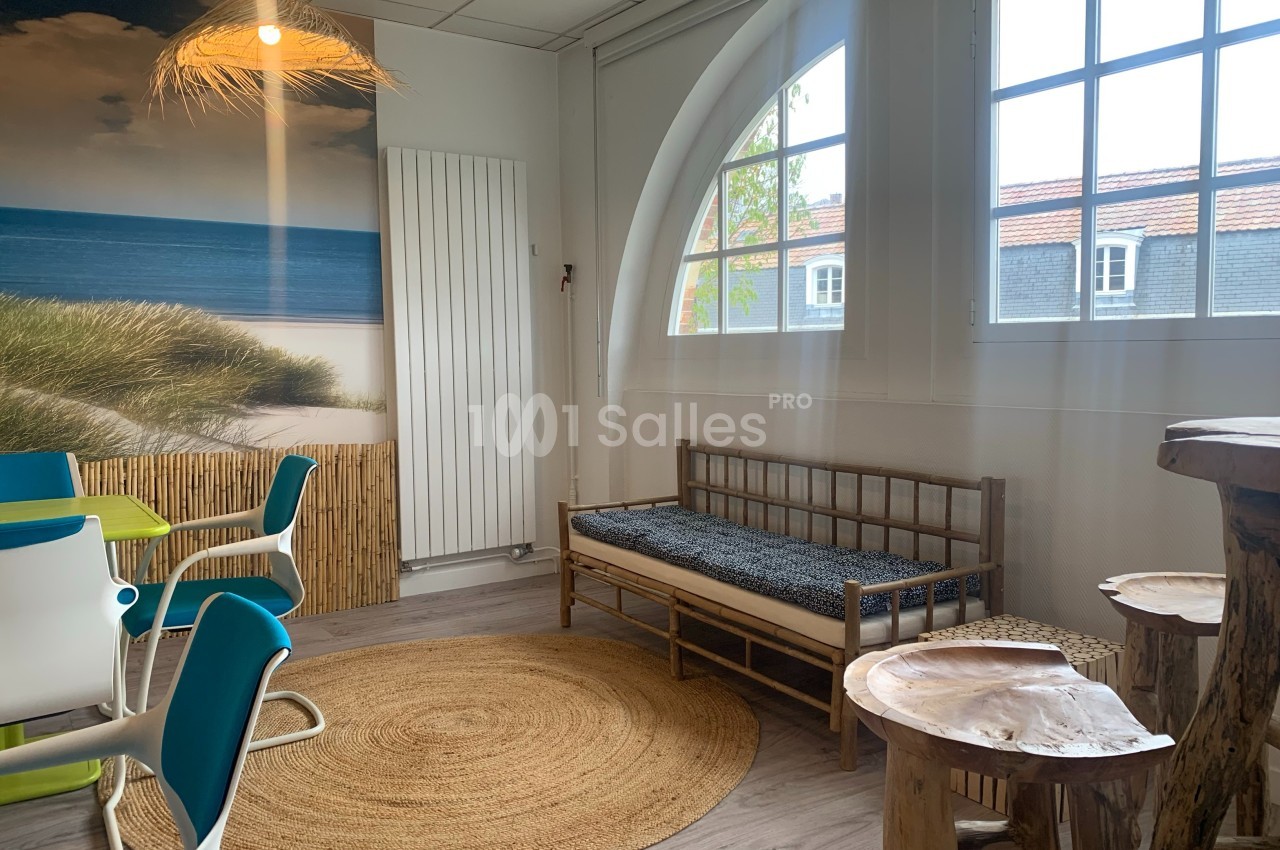 Salle lumineuse avec décoration naturelle, comprenant un canapé en bois, une table en tronc d'arbre et des chaises colorées.