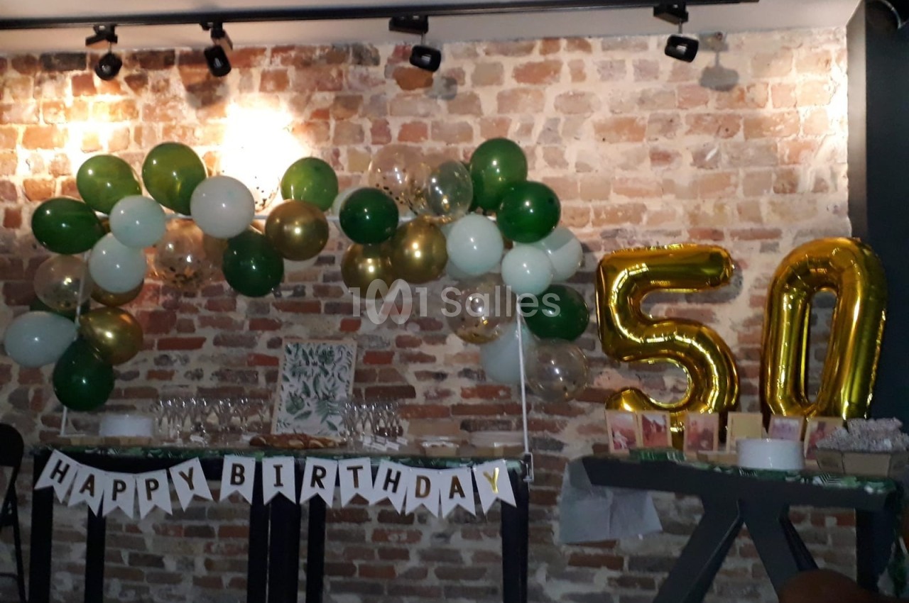 Décoration d'anniversaire avec ballons verts, blancs et dorés, guirlande ’Happy Birthday’ et ballons dorés formant ’50’.