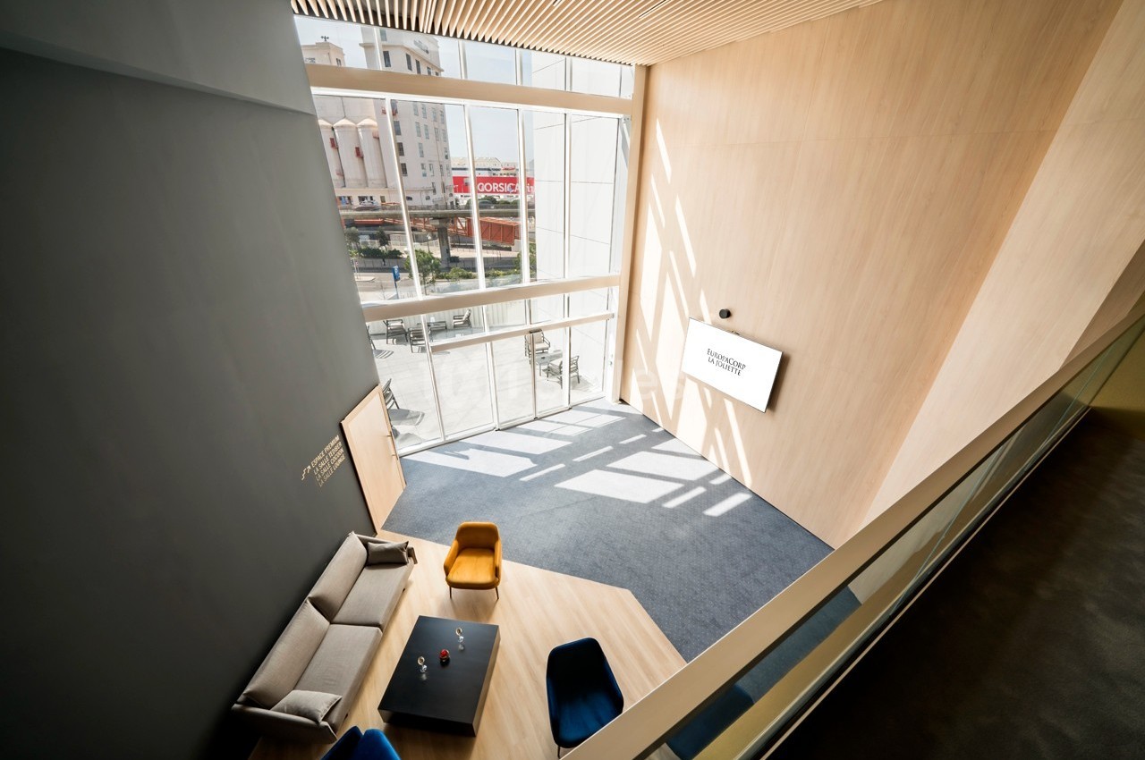 Vue intérieure d'un espace moderne avec canapé, fauteuils colorés, table basse et grande baie vitrée laissant entrer la…