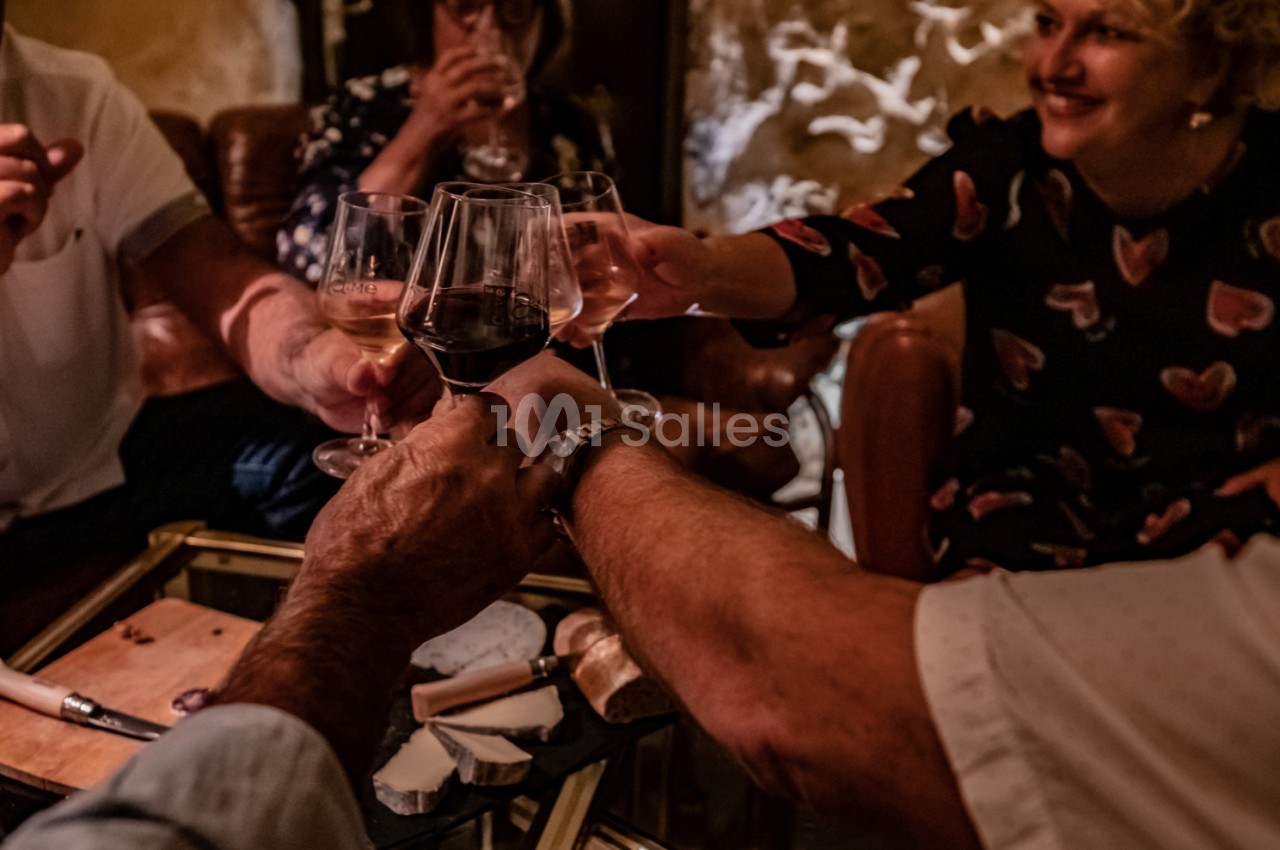 Des personnes trinquent avec des verres de vin autour d'une table dans une ambiance chaleureuse et conviviale.