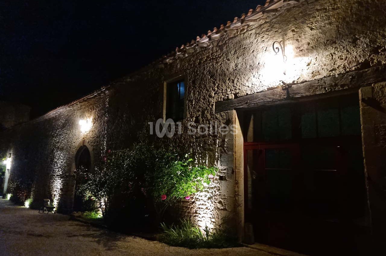 Façade en pierre d'un bâtiment ancien éclairée par des lumières extérieures, de nuit.
