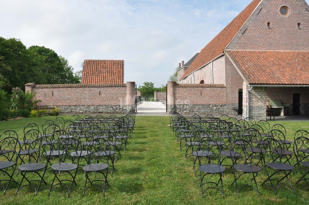 Chaises métalliques alignées sur une pelouse devant un bâtiment en briques rouges dans un cadre extérieur.