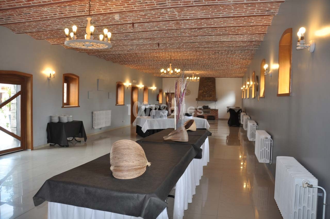 Salle de réception avec plafond en briques, tables recouvertes de nappes noires et décorations en osier.