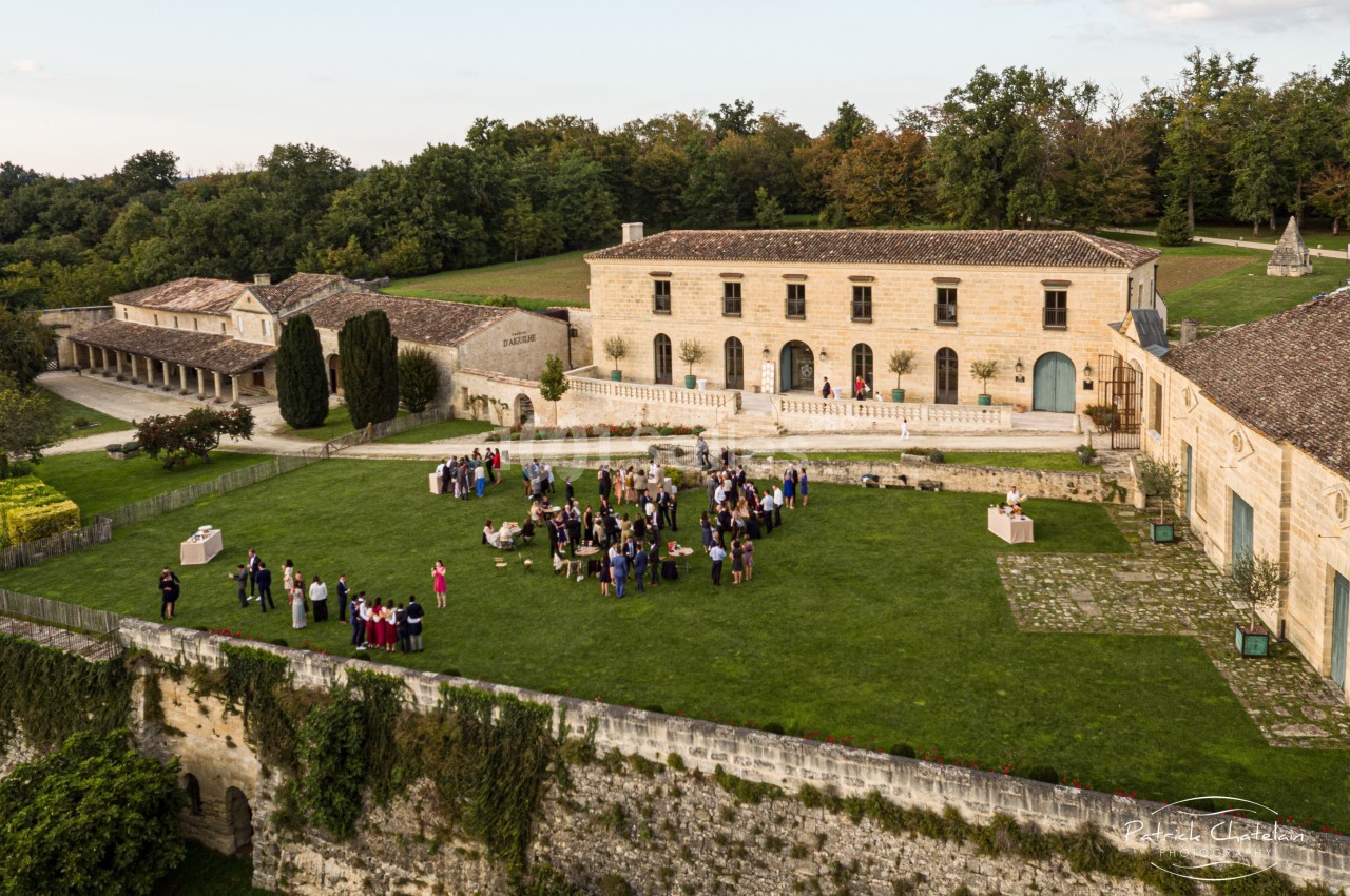 Vue aérienne d'un domaine avec une pelouse où des personnes sont rassemblées pour un événement en plein air.