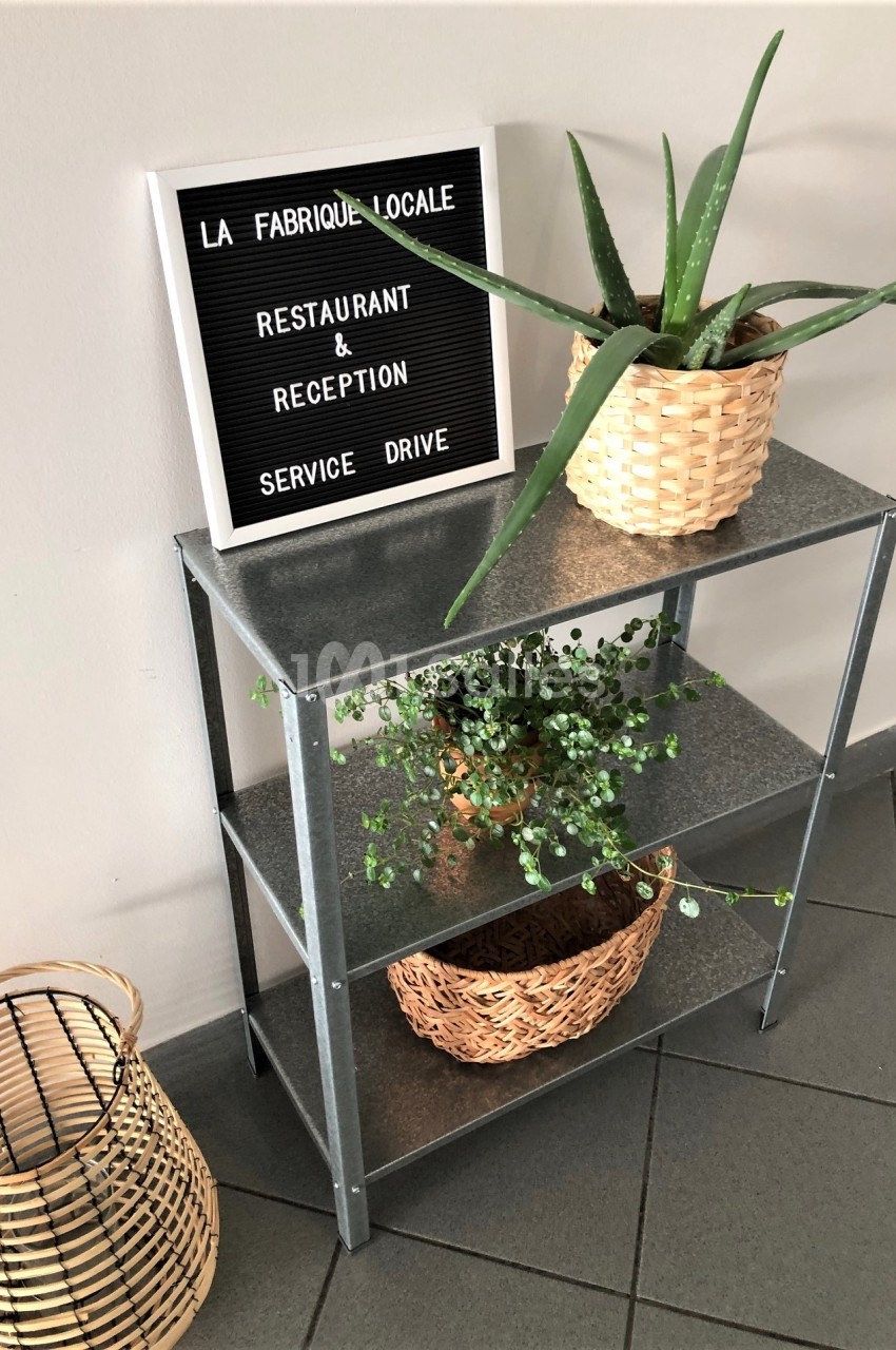 Étagère métallique avec plantes en pots tressés et panneau indiquant un restaurant et service drive.