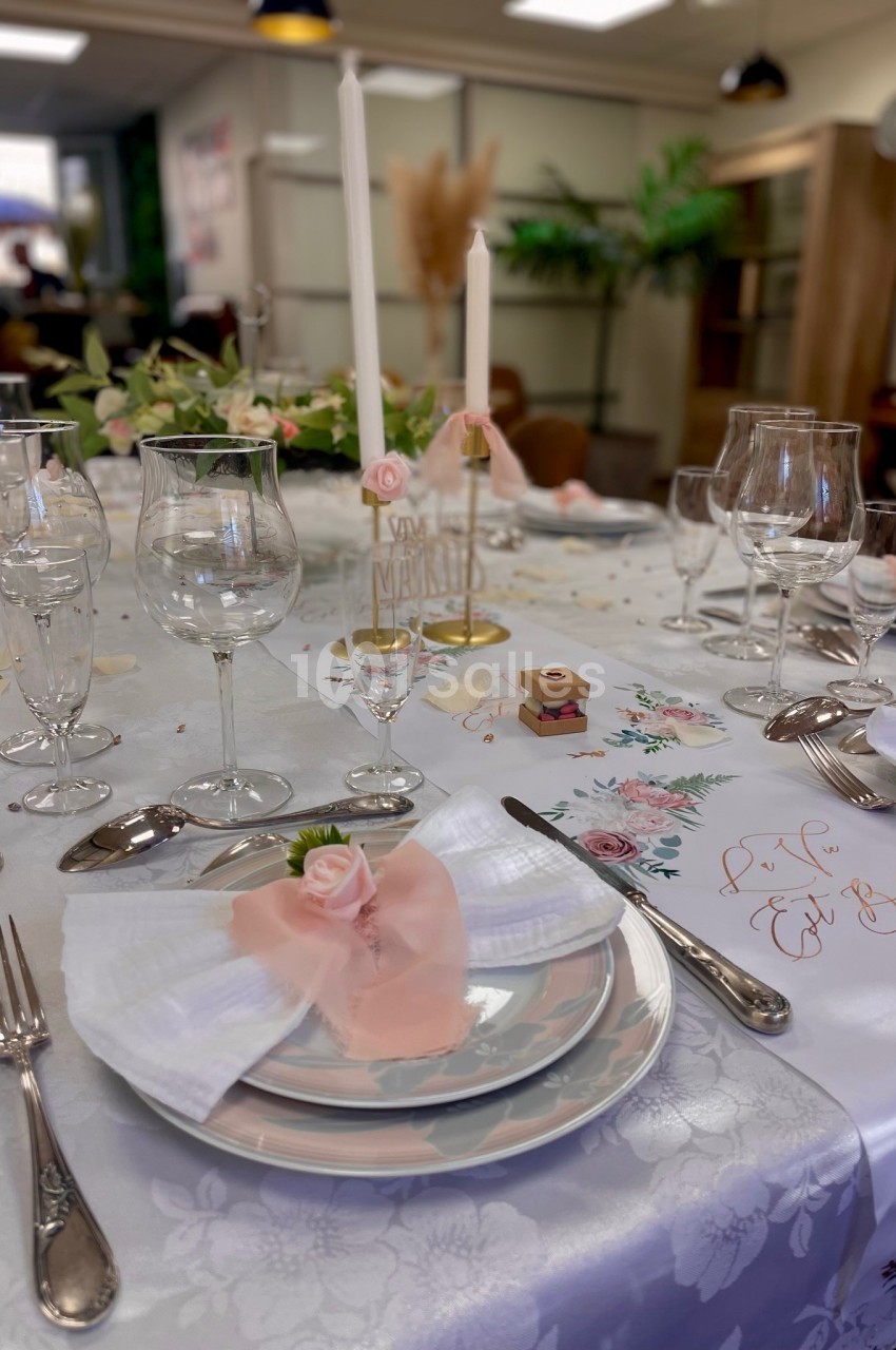 Table élégamment dressée avec vaisselle raffinée, bougies et décorations florales dans un cadre lumineux.