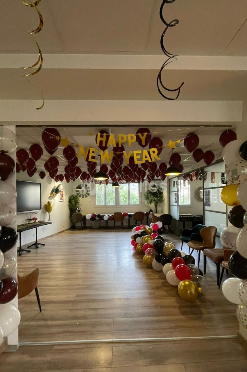 Décoration de salle pour le Nouvel An avec ballons colorés, guirlandes et une bannière ’Happy New Year’.
