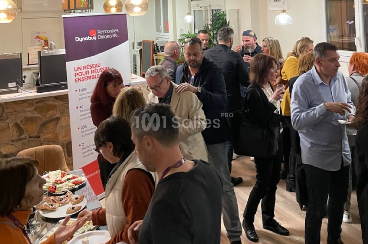 Groupe de personnes échangeant lors d'un événement professionnel dans un espace intérieur convivial.