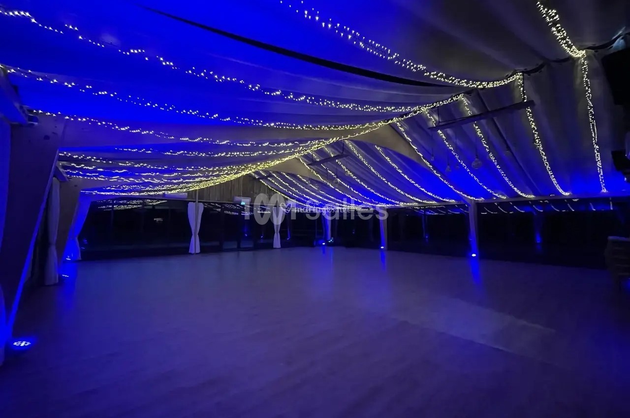 Plafond décoré de guirlandes lumineuses bleues et blanches dans un grand espace intérieur sombre.