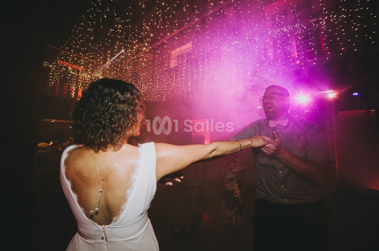 Un couple danse sous des lumières féeriques dans une ambiance festive et tamisée.