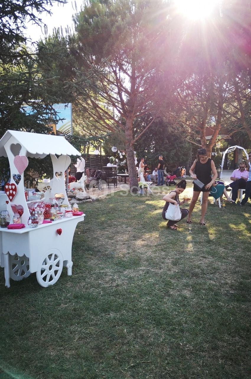 Stand décoratif avec des bonbons dans un parc, entouré d'arbres, de personnes assises et d'enfants jouant.